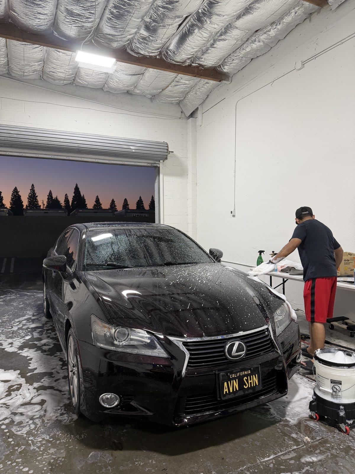 Hand-washing a black Lexus GS in the R-Spec shop bay