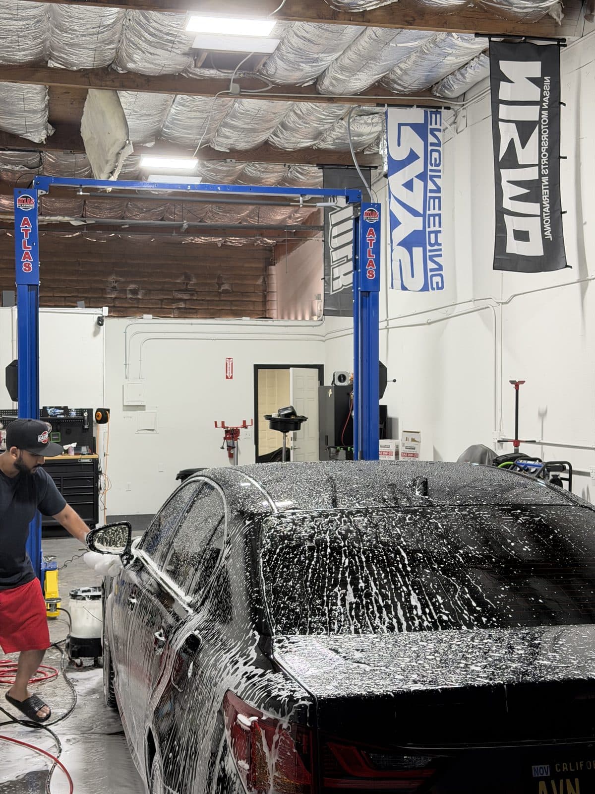 Black Lexus GS covered in foam under the two-post lift